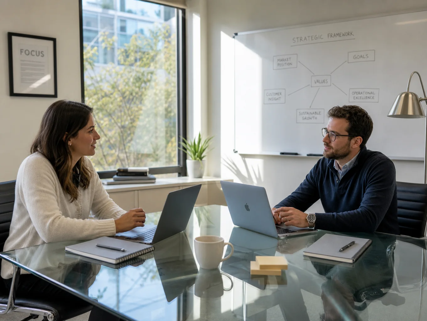 Two young executives sharing a lighthearted moment over laptops